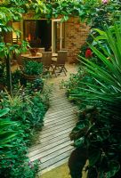 Petit jardin de ville avec plantation verte tropicale. Patio couvert avec Loquat sur cadre en bois. Table et chaises. Portes doubles pour loger - Nouvelle-Galles du Sud, Australie