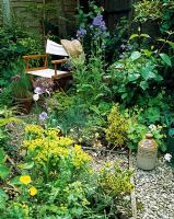 Parterres herbacés mixtes avec chemin de gravier menant à la chaise du directeur dans un coin calme du jardin