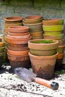 Vieux pots en terre cuite empilés sur une table d'empotage avec une truelle