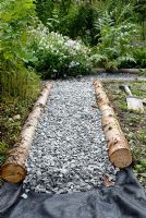 Pose d'un chemin de jardin avec une membrane de contrôle du bois rustique, du gravier et des mauvaises herbes