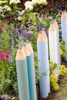 Clôture faite de crayons de couleur géants à côté de parterres de fleurs