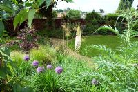 Parterre de fleurs autour de la pelouse, y compris Eremurus robusta et Allium 'Gladiator'