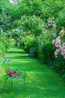 Chemin d'herbe avec sièges métalliques et parterres de fleurs mixtes - Les Jardins d ' Angélique, France