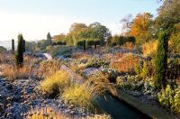 Un ruisseau d'eau avec du givre sur les plantes vivaces et les graminées ornementales à Broughton Grange, Oxfordshire