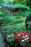 Jardin en août avec maison d'été peinte en bleu et Nicotiana et Impatiens en pots - Barleywood, Hampshire