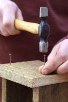 Étape par étape 2 de la fabrication d'une maison d'insectes pour les insectes hibérants à partir de bois récupéré - Martelage dans les clous pour construire une boîte en bois