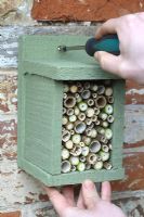 Étape par étape 7 de la construction d'une maison anti-insectes pour les insectes hibérants à partir de bois récupéré - Installation de la boîte à insectes sur un mur abrité