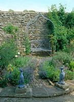 Jardin d'herbes avec statues de lévrier en plomb et siège en métal, Nepeta mussinii, Helianthemum 'Highdown Apricot', Foeniculum vulgare 'Purpureum', Calamintha, Standard Honeysuckle et Rosa 'Agnes' - Lawkland Hall, Yorkshire