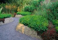 Les murs en briques incurvées en pente produisent une gorge ou un passage semblable à un ravin à travers un étang naturaliste au fond de ce jardin de démonstration - BBC Kings Heath
