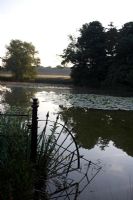 Tôt le matin, vue sur le lac avec des nénuphars et des rampes décoratives en fer - Narborough Hall