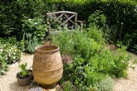 Banc en bois dans la zone de gravier avec une urne en terre cuite vide avec Nigella, Alliums et Geranium plamatum - Eldenhurst