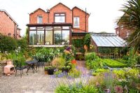 Arrière d'une grande maison individuelle avec véranda et jardin bien planté