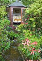 Summerhouse avec Acers matures et arbustes avec ruisseau au jardin Four Seasons NGS, Staffordshire