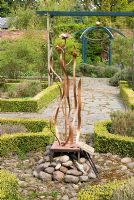 'The Singing Rose 'conçu et réalisé par Cilia West au centre de la roseraie formelle, des bordures Buxus et des sentiers de l'ardoise Westmorland - Poulton Hall, jardin NGS, Cheshire