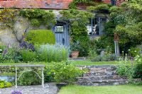 Étapes menant à travers les plantations de valériane et de salvias à la porte en chêne d'origine, Hayes Farmhouse, East Sussex