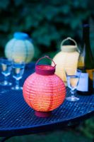Lanternes colorées et verres sur une table de jardin