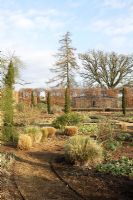 Vue sur jardin clos conçu par Tom Stuart-Smith, avec des graminées, des cyprès italiens et des passerelles de charme - Broughton Grange en février