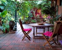 Coin salon avec coussins roses entourés de plantations tropicales
