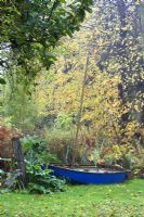 Parterres de fleurs et vieux voilier dans un jardin de campagne informel en octobre.