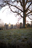 Rousham en hiver. Vue de la maison Rousham attraper le soleil d'hiver à travers champ givré avec arbre à feuilles caduques mature.
