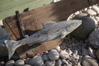 Jardin inspiré de la mer. Détail de poissons sculptés sur bois sur la plage de galets.