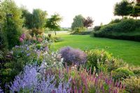 Jardin à la française avec parterres de fleurs et pelouse. Teucrium, Perovskia, géranium, Echinacea purpurea 'Envie verte'