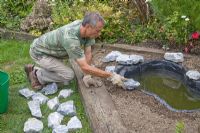 Projet d'étang de jardin - étape par étape - ajout de pierres de bordure pour cacher la doublure