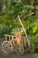 Vieux chariot en bois comme élément de jardin contenant un pot avec des plantes annuelles d'été. 'Hazelwood', Jacqueline Iddon Hardy Plants, jardin NGS, Lancashire