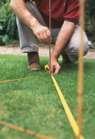 Guide étape par étape pour mesurer un jardin. Définissez des cannes ou des piquets comme marqueurs à intervalles réguliers, par exemple à 2 m l'un de l'autre, pour donner une référence visuelle facile lorsque vous regardez autour de votre jardin.