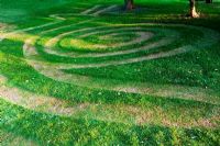 Conception d'escargot coupée en herbe dans la zone boisée avant. Mathern House, Mathern, Monmouthshire, Pays de Galles. Début juin. Ouverture du jardin pour le programme des jardins nationaux.