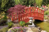 Pont rouge sur la piscine menant à la rocaille dans le jardin japonais à Mount Pleasant Garden, Kelsall, Cheshire
