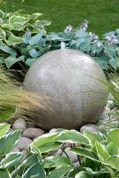 Élément d'eau en pierre ronde parmi Hosta et Stipa tenuissima - The Urban Retreat, médaillé de bronze au RHS Hampton Court Flower Show 2010