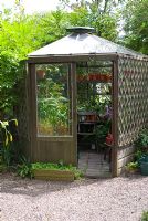 Serre en bois hexagonale pleine de plantes tendres à Crossing House Garden, Cambridgeshire