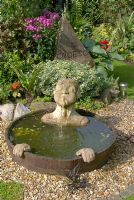 Une pièce d'eau à demi-baril avec bec et mains submergés, cadran d'horloge en plateau de table orné peint et sculpture en pierre sculptée avec 'Croeso' - bienvenue en gallois à 'Trevinia', Stubbins, Lancashire NGS