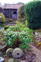 Affûtage des pierres à l'avant-plan stable à l'arrière-plan d'un petit jardin de chalet - Court Lane Farm, Wiltshire