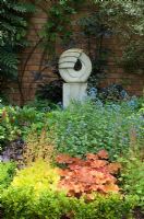 Petit jardin urbain avec sculpture en pierre, la plantation comprend Heuchera, Brunnera, Sambucus nigra, Mahonia et Euonymus - jardin NGS, Foster Road, Peterborough, Cambridge