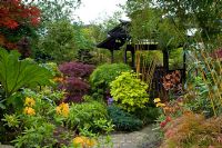 Chemin de pavage fou à travers un jardin de style oriental avec des parterres de Acer, Bamboo, Azalea et Gunnera. Tony et Marie Newton, Walsall, Royaume-Uni