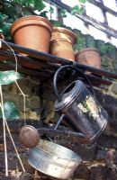 Ancien arrosoir et pots en terre cuite gardés à l'extérieur dans le jardin