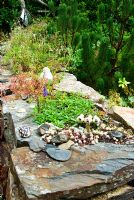 Mur de pierre planté de sedums et alpins et décoré de petites figurines et statuettes au profit des plus jeunes - Pinsla Garden, Cardinham, Cornwall