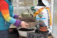 Femme tamisant le compost pour aérer le proir avant le semis, février