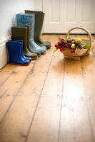 Quatre paires de bottes en caoutchouc d'une famille de jardinage dans le couloir avec un trug en bois de tulipes