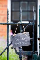 'Dans le jardin', écrit à la craie sur ardoise, accroché à un portail d'entrée