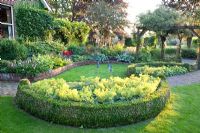 Jardin avec parterres courbes, pergolas et parterre de fleurs semi-circulaire d'Alchemilla mollis - Manteau Ladys avec bordure Buxus - Broekhuis Garden