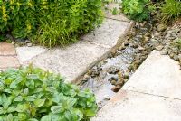 Rill d'eau bordé de dalles de pavage dans le jardin du chalet