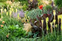 Jardin englouti est une masse de fleurs colorées à la fin de l'été, y compris Kniphofias, Cannas, Dahlias, Eucomis et graminées - île de Wight, Royaume-Uni
