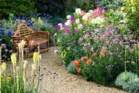 Des chemins de gravier à travers le jardin englouti sont bordés d'une masse de vivaces et d'annuelles colorées, y compris Cleomes, Agapanthus, Eucomis, Dahlias, Verbena bonariensis et Kniphofias - Isle of Wight, Royaume-Uni