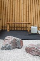 Un coin salon avec des rochers et un chemin de gravier soutenu par une clôture en bambou dans le jardin à thème japonais - 'Less and More' garden - RHS Hampton Court Flower Show 2011