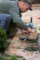 Homme marquant la tuile de jardin avant de couper avec une meuleuse d'angle pour s'adapter au plan de la terrasse du jardin.