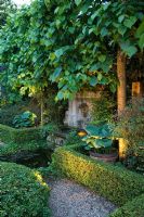 Jardin méditerranéen de style formel avec une haie basse entourant l'étang, les hostas en pots, l'éclairage, les chemins de gravier et les limes blanchies - Madrid, Espagne