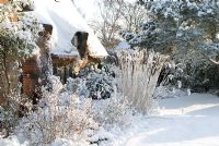 Chaumière et brique dans la neige, le parterre de fleurs comprend Spiraea et l'herbe Miscanthus sinensis 'Silberfeder'. Gowan Cottage